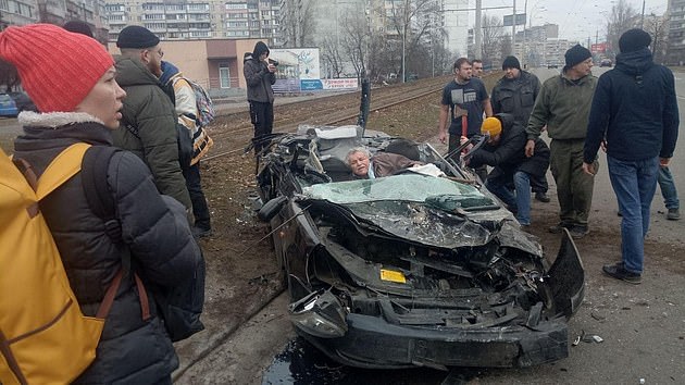 A military vehicle has been filmed crashing into and rolling over a civilian car near Ukraine's capital of Kyiv. Pictured: The aftermath of the crash, with the driver trapped inside
